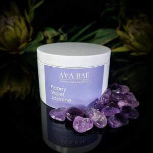 Peony Violet Jasmine Travel Candle by Ava Bae, elegantly presented in a sleek container, accompanied by polished purple crystals, embodying luxury and sophistication.