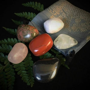 Exquisite arrangement of the Pregnancy Tumbles crystals, showcasing a variety of stones in a sophisticated pouch on a dark backdrop, highlighting delicate energy support for pregnancy.